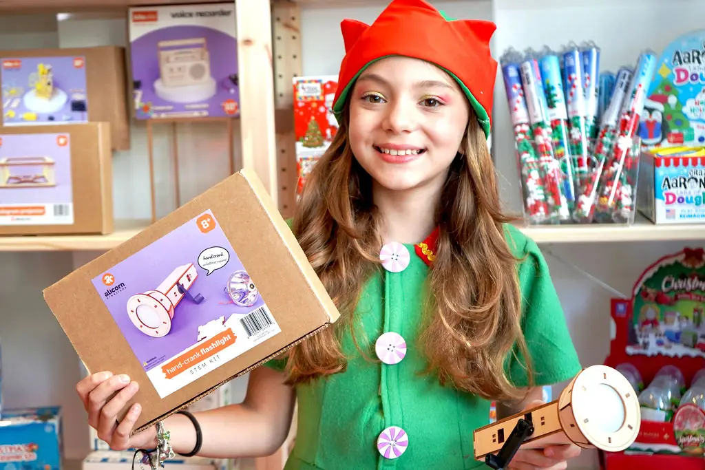 Young elf holding a boxed craft kit in the Elf Factory store